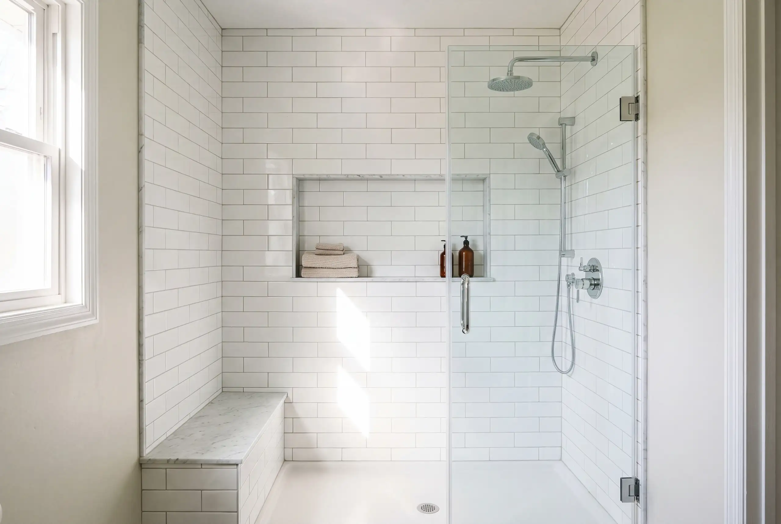 A tub to shower conversion in a standard alcove with white subway tile to the ceiling and a glass door