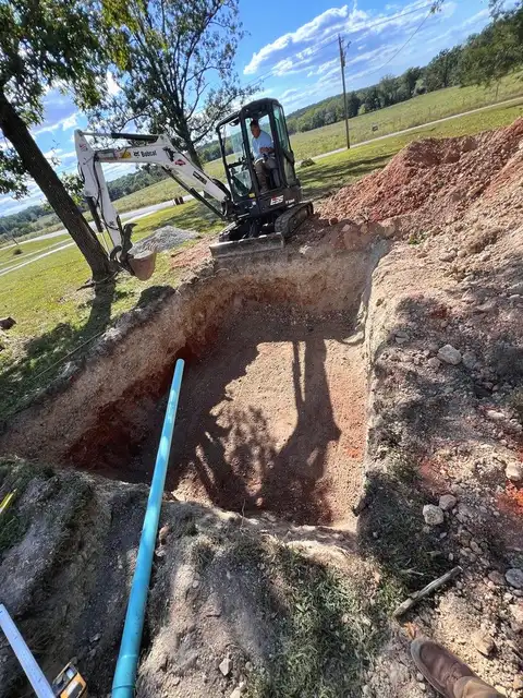 Mini excavator digging a trench for a new water line in a customer's yard