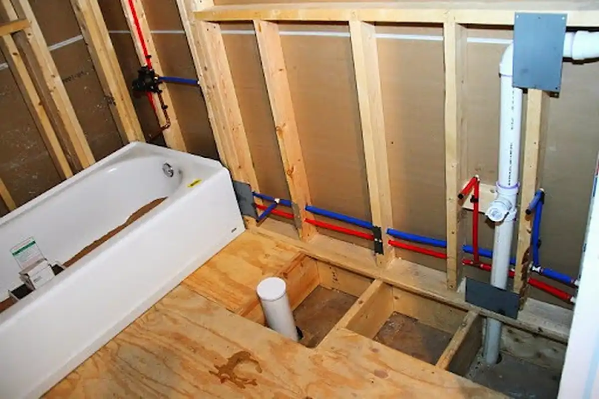 New red and blue PEX water lines run through the framing of a bathroom