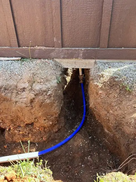 Blue water line laid in a trench beside a house