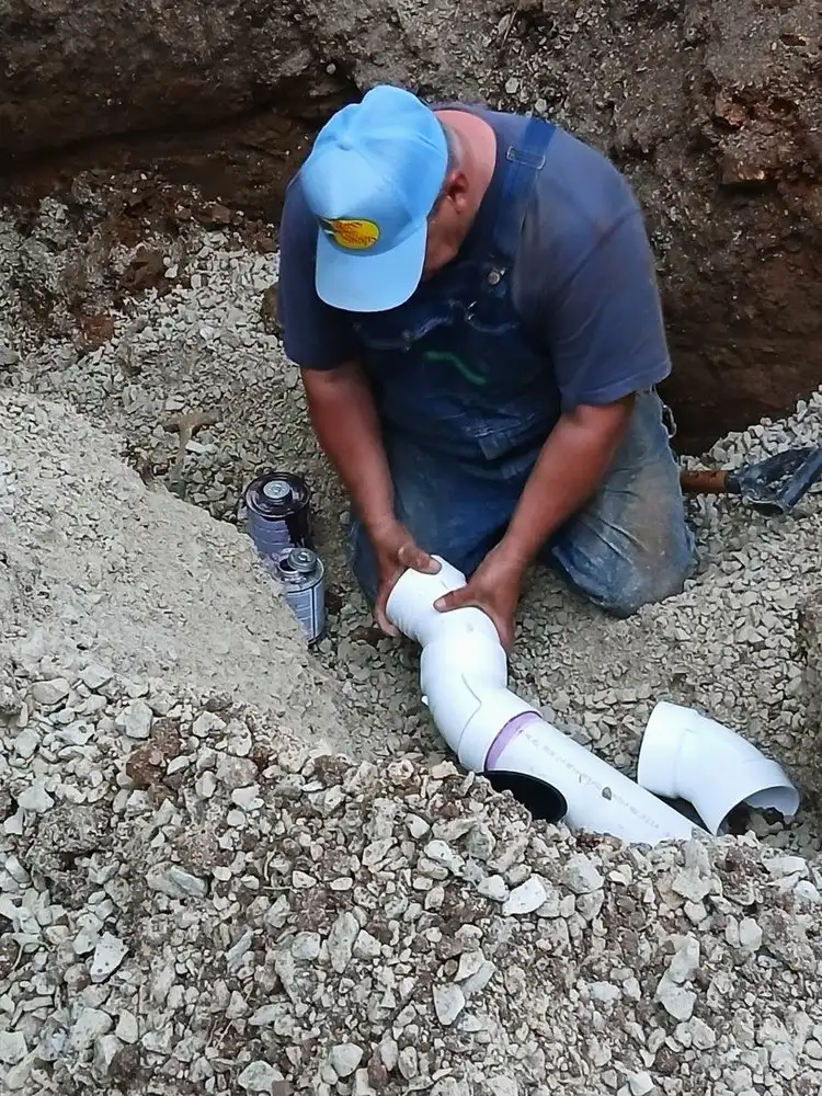 Sewer line fittings being glued in a gravel bed